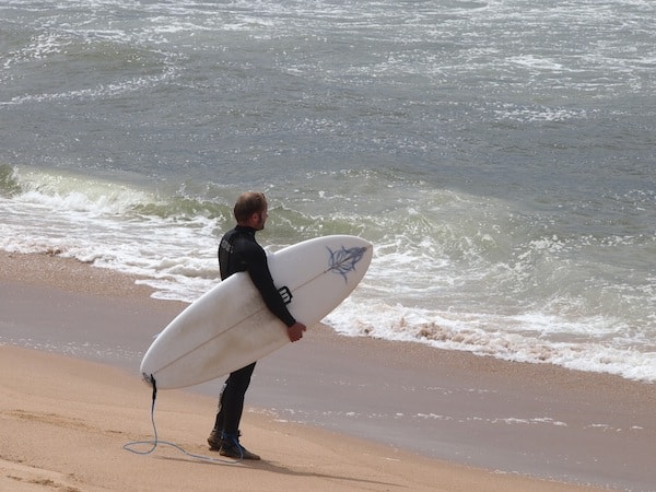 David ist bereits zum achten Mal im MellowMove Surfcamp zugegen und bereits ein erfahrener Surfer. Wir folgen seinem wachen Blick über die Wellen, als er prüft welche Einstiegsstelle er heute für das Surfen wählt.