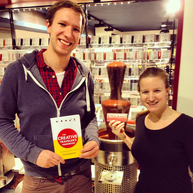 Florian Figl, happily holding "The Creative Traveler's Handbook" in hand while meeting at the chocolate factory where he works (can you see the chocolate fountain in the back?)!