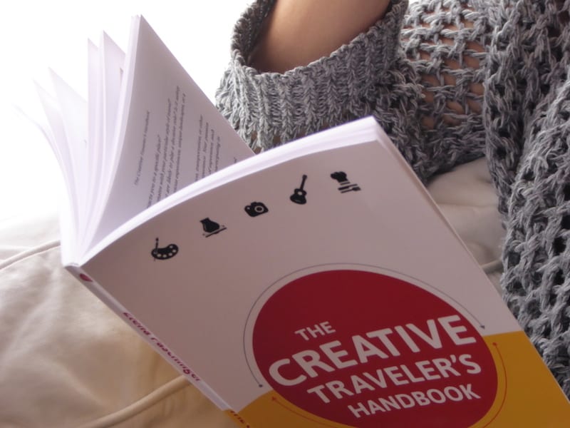 Nicole Biarnes reading "The Creative Traveler's Handbook" back home on her couch in Barcelona.