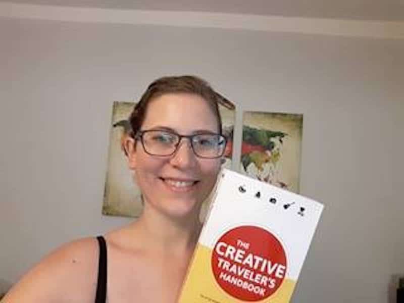 Tina in her home country Burgenland, proudly holding up her copy of "The Creative Traveler's Handbook".