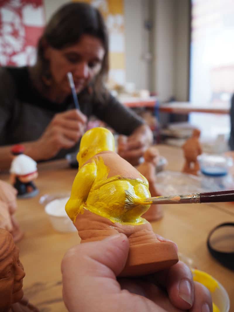 Der kreativen Vielfalt ist beim Caganer-Workshop keine Grenze gesetzt: Janett bemalt hier gerade ihren Homer Simpson-Caganer, während ich an meiner Prinzessin mit Häufchen bastle. Nicole hat passend dazu übrigens einen längeren Bericht geschrieben, in dem sie Euch vieles amüsant und detailvoll schildert!