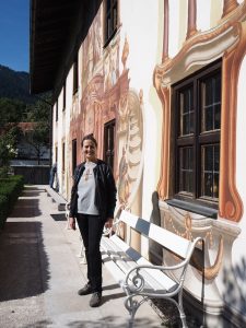 ... meine charmante Ortsführerin ... ist überdies auch Holzbildhauerin: Sie erklärt mir die Geschichte von Oberammergau anhand der berühmten Lüftlmalerei ...