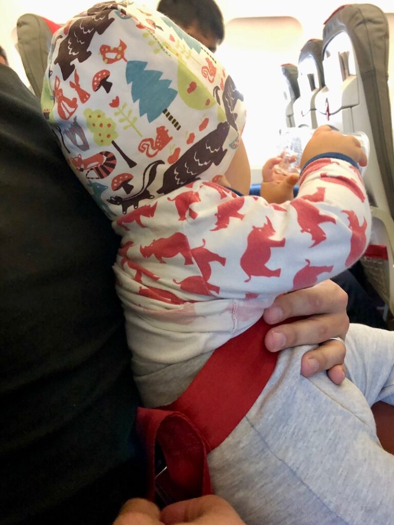In the aircraft itself, the baby is given its own small harness and is thus "attached" to the harness of a parent. I recommend - from twofold personal experience - breastfeeding (or giving bottles) during the climb and descent to prevent possible earaches for the baby.